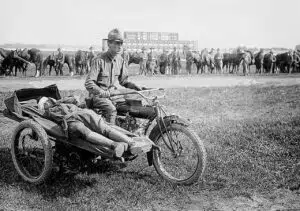 Soldier carrying another injured soldier in sidecar of a bike