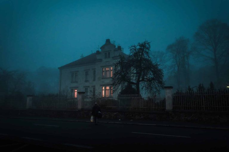 A creepy, haunted looking old house at nighttime