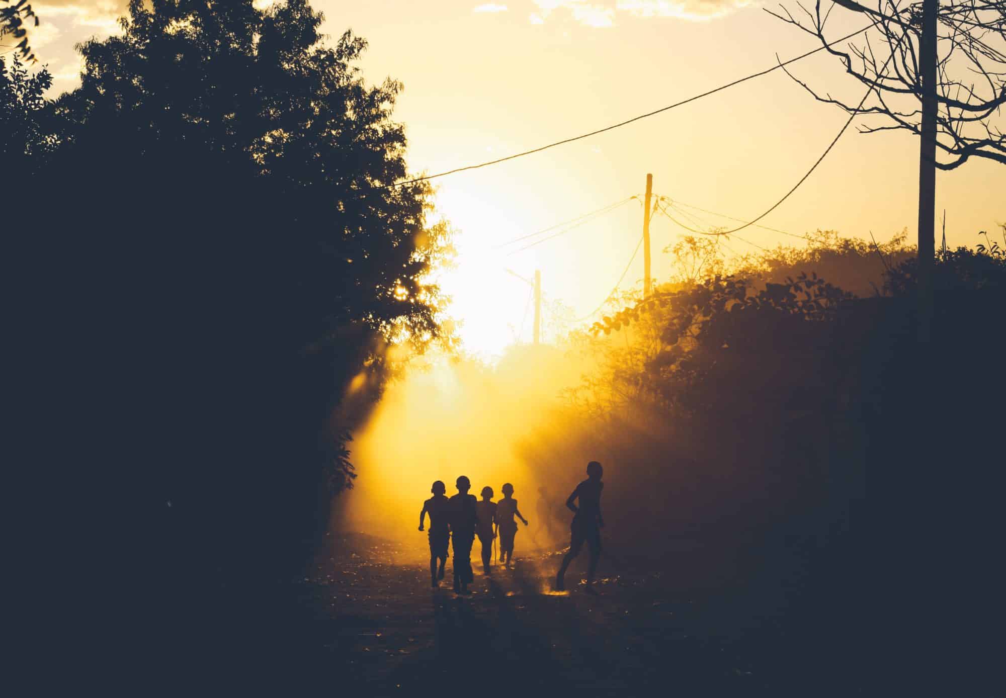 Children running in a field at dusk