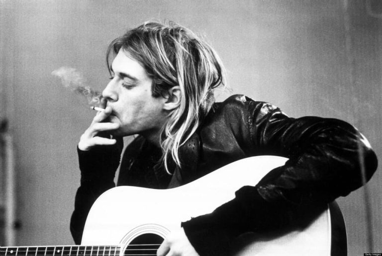 Kurt Cobain smoking cigarette and holding acoustic guitar