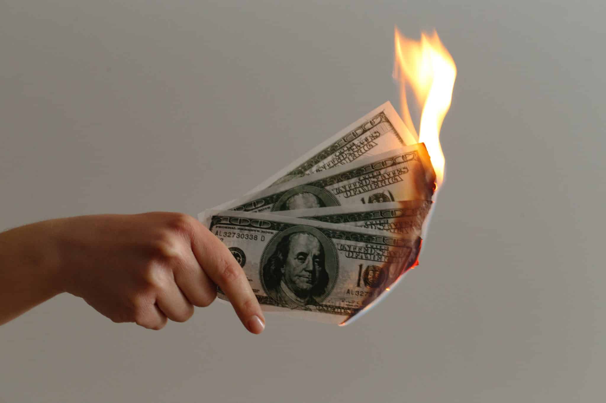 Person holding $100 bills on fire