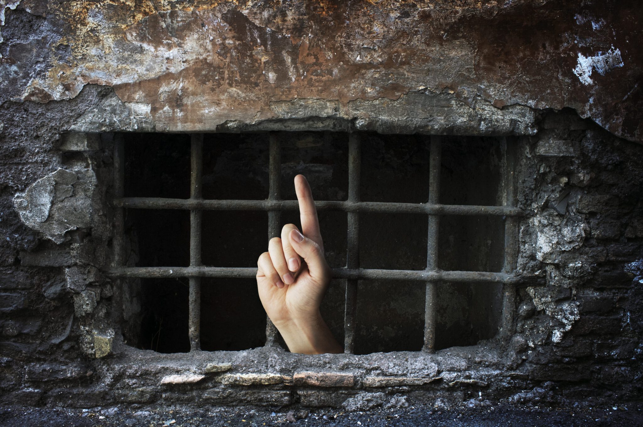 Conceptual image of a hand reaching out from a dungeon.