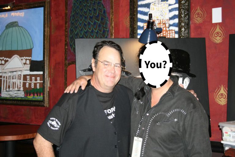 An image of Dan Aykroyd with a second person whose face is ‘blanked’ out and it says “You?” over top