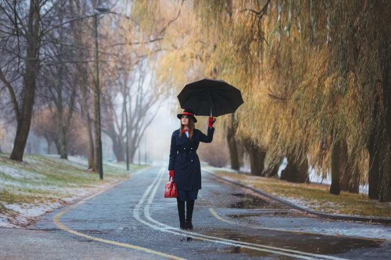 A girl in a hat walks in the rain. Mery Poppins goodbye!