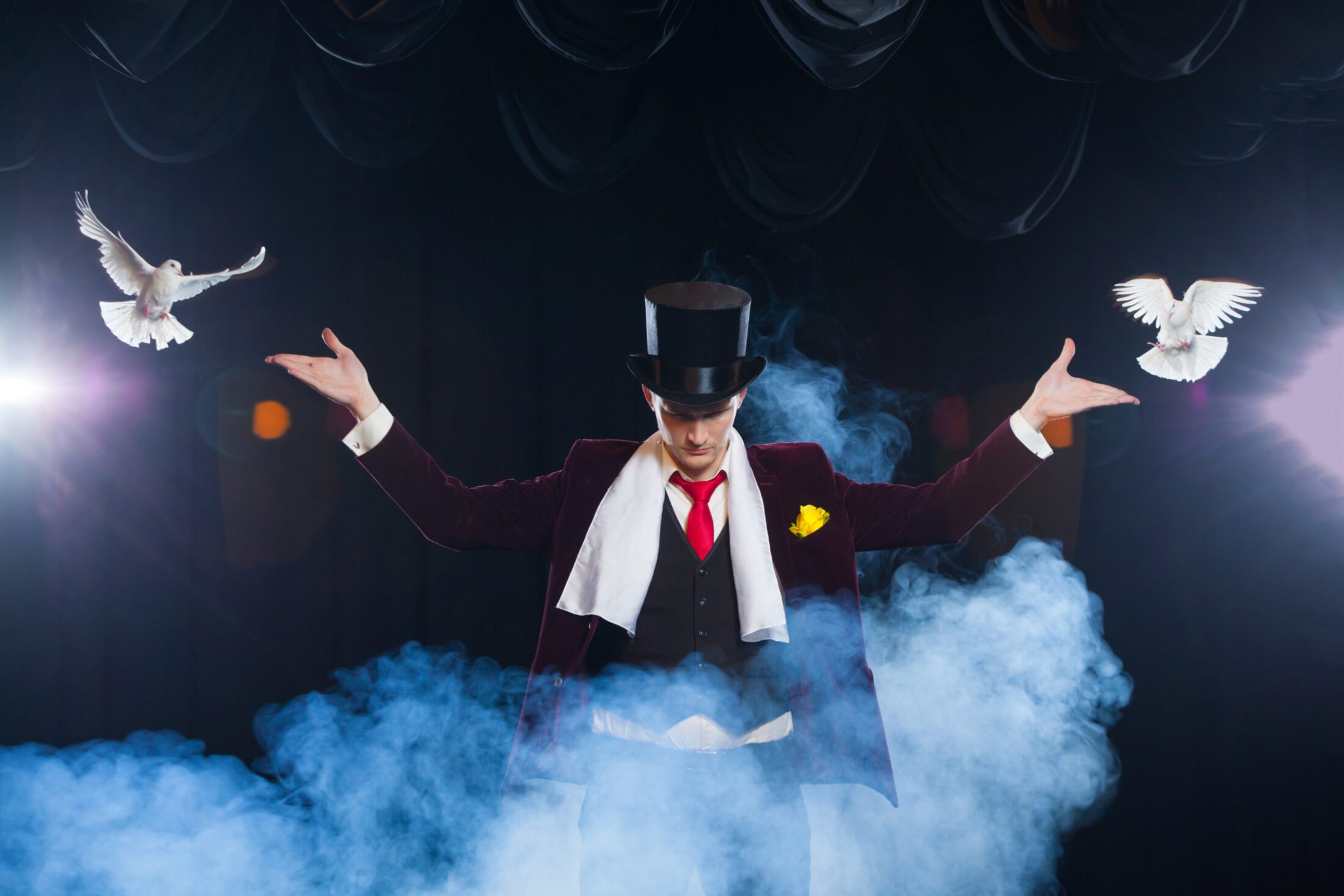 The magician with a two flying white Doves. on a black background. shrouded in a beautiful mysterious smoke