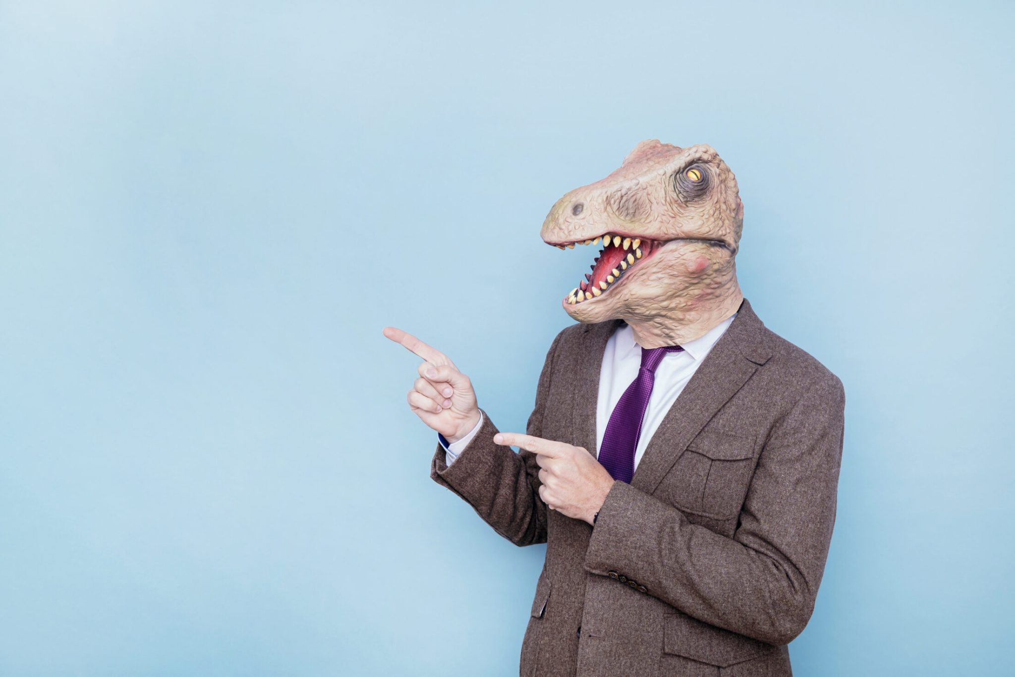 Euphoric man with lizard head pointing to the side on blue background.