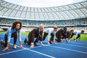 Side view photo of confident multi ethnic business people lined up getting ready for race on modern sport track. Stadium as a background