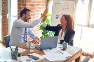 Two businesspeople smiling and high-fiving